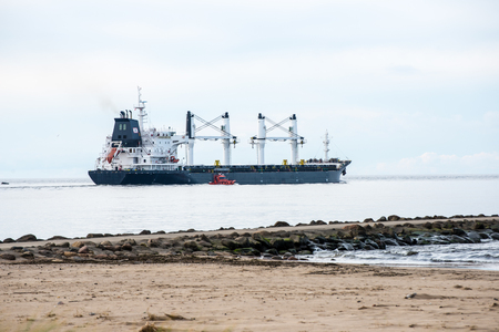 cargo ship is leaving port sailing away. riga. latviaのeditorial素材