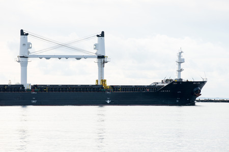 cargo ship is leaving port sailing away. riga. latviaの写真素材