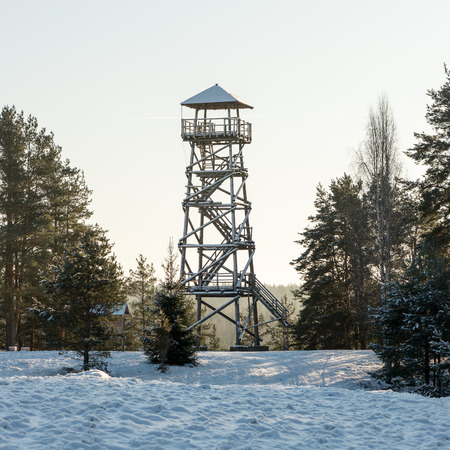 beautiful snowy winter landscape with watchtower in forest and blue skyの写真素材