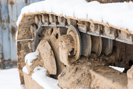 Detail of caterpillar track in construction site with dust and snowの写真素材