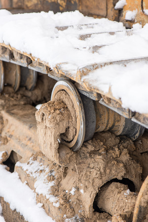 Detail of caterpillar track in construction site with dust and snowの写真素材