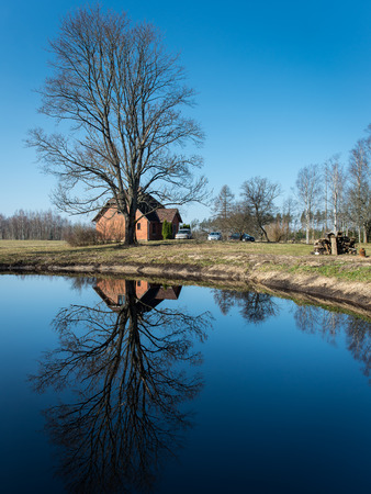 reflections of country house in the pond with trees and blue skyのeditorial素材