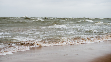 baltic beach in fall with clouds and waves towards deserted dunes. cloudy day