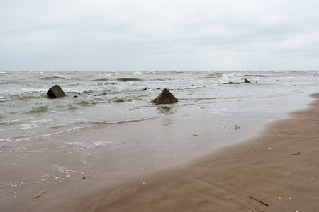 baltic beach in fall with clouds and waves towards deserted dunes. cloudy dayの写真素材