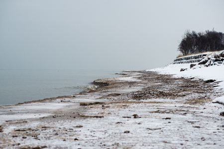 frozen beach view by the baltic sea with sand and ice in waterの写真素材