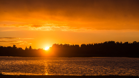 Beautiful dramatic sunset over the lake with clouds and reflectionsの写真素材