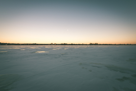 frozen beach in cold winters day with colorful sky and iceの写真素材