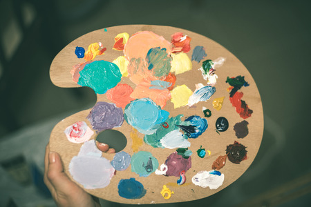artist painting with acrylic colors and mixing tones on the pallet. blur background abstract photo - vintage effectの写真素材