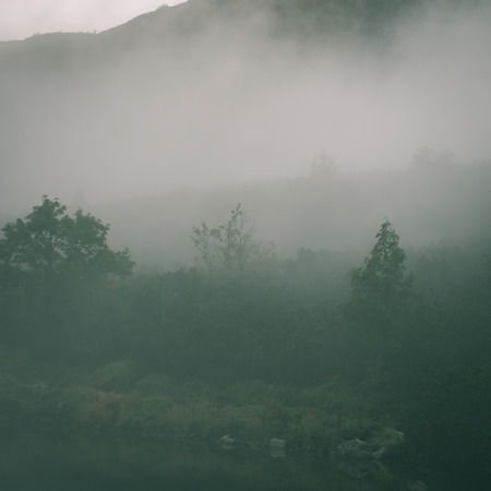 landscape with mountains trees and a river in front in autumn - instant vintage square photoの写真素材