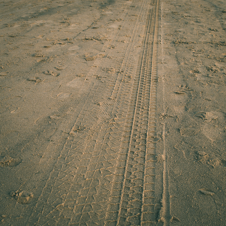 car tyre tracks on the beach sand in perspective - instant vintage square photo