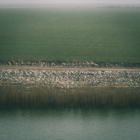 dramatic clouds over the river in misty morning in spring with reflections in water - instant vintage square photoの写真素材