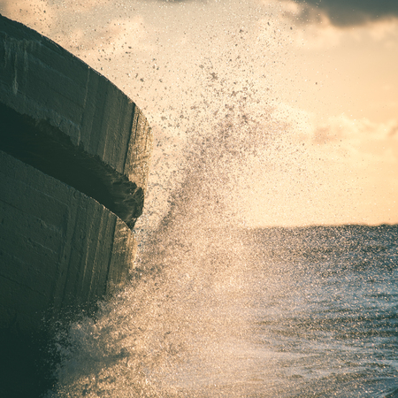 waves crushing over rocks and ruins of old fort at sunset on the beach - instant vintage square photoの写真素材