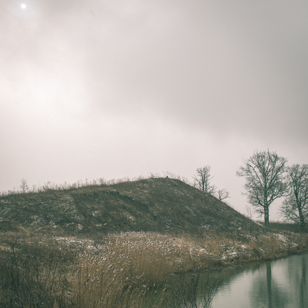 dramatic clouds over the river in misty morning in spring with reflections in water - instant vintage square photoの写真素材