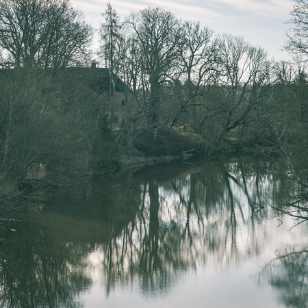 dramatic clouds over the river in misty morning in spring with reflections in water - instant vintage square photoの写真素材