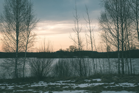 sunset over the river Daugava with dramatic colorful sky and tree silhouettes - vintage green retro effectの写真素材