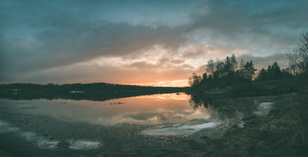 sunset over the river Daugava with dramatic colorful sky and tree silhouettes - vintage green retro effectの写真素材