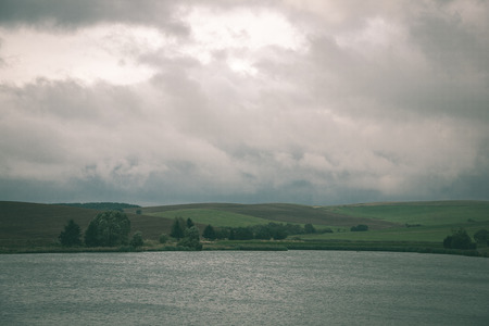 view to the mountain river in summer surrounded by forest and sandstone cliffs - vintage green lookの写真素材