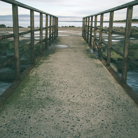 old bridge with rusty metal rails near sea port - instant vintage square photoの写真素材