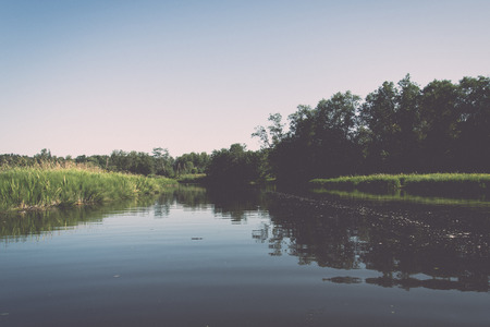 Picturesque river view with clouds and trees in the background - retro, vintage style look
