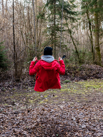 young woman in red dress using swings in spring forest having funの写真素材