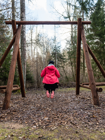 young woman in red dress using swings in spring forest having funの写真素材