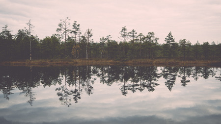 reflections in the lake water at sunrise - retro, vintage style lookの写真素材