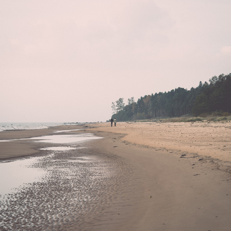 Shoreline of Baltic sea beach with rocks and sand dunes under clouds. Vintage effect.の写真素材