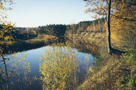 scenic autumn colored river in country with trees and reflections. Vintage photography effect. Retro...