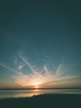 beautiful sunrise over country lake with orange clouds and reflections - vintage green lookの写真素材