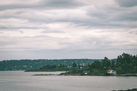 typical norway sea shore countryside landscape view with islands and trees - vintage green lookの写真素材