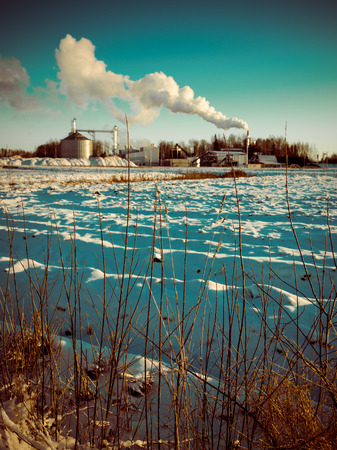 industrial park with chimney and white smoke on blue sky - retro vintage lookの写真素材
