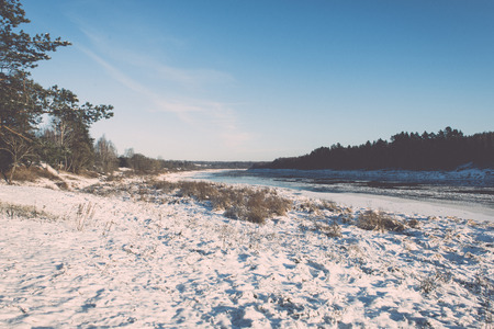 beautiful snowy winter landscape with frozen river and blue sky - retro vintage effectの写真素材