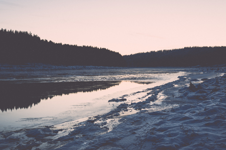 beautiful snowy winter landscape with frozen river and blue sky - retro vintage effectの写真素材