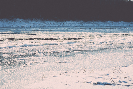 beautiful snowy winter landscape with frozen river and blue sky - retro vintage effectの写真素材