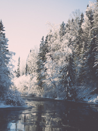 snowy winter river landscape with snow covered trees and blue sky - retro vintageの写真素材