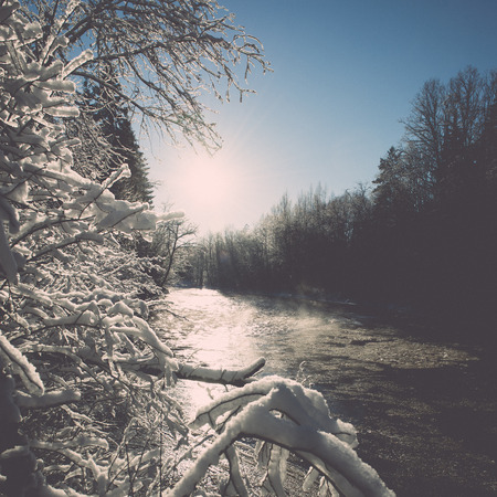 snowy winter river landscape with snow covered trees and blue sky - retro vintageの写真素材