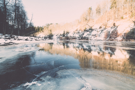 frozen river in winter with sandstone cliffs and ice blocks. Gauja National Park. Latvia. -vintage retro effectの写真素材