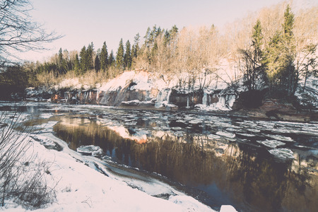 frozen river in winter with sandstone cliffs and ice blocks. Gauja National Park. Latvia. -vintage retro effectの写真素材