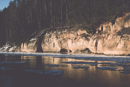 frozen river in winter with sandstone cliffs and ice blocks. Gauja National Park. Latvia. - retro vintage effectの写真素材