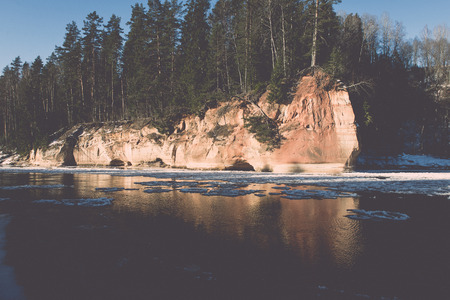 frozen river in winter with sandstone cliffs and ice blocks. Gauja National Park. Latvia. - retro vintage effectの写真素材