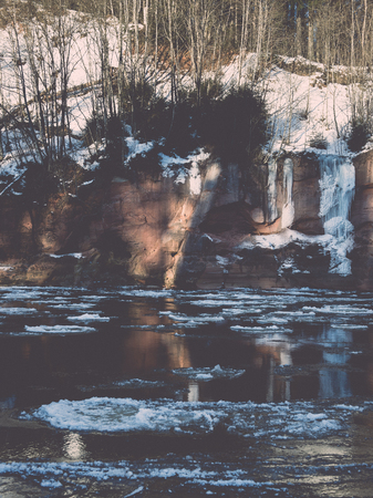 frozen river in winter with sandstone cliffs and ice blocks. Gauja National Park. Latvia. -vintage retro effectの写真素材