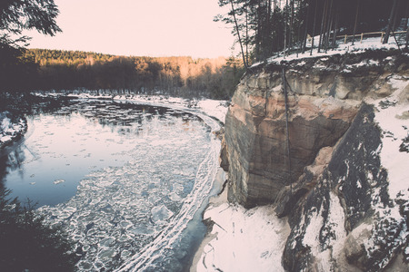 frozen river in winter with sandstone cliffs and ice blocks. Gauja National Park. Latvia. - retro vintage effectの写真素材