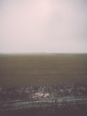 dramatic clouds over the river in misty morning in spring with reflections in water - retro vintage looking effectの写真素材