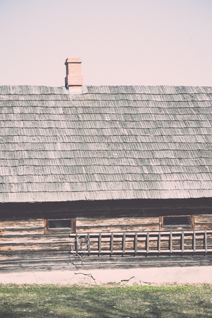 old countryside house with brick chimney and wooden roof - retro vintage film effectの写真素材