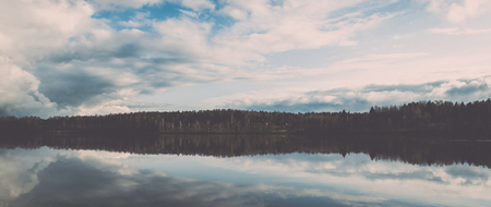 dramatic clouds over the river in misty morning in spring with reflections in water - retro vintage looking effectの写真素材