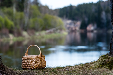 beautiful wooden woven basket in front of forest river with blur background and copy spaceの写真素材