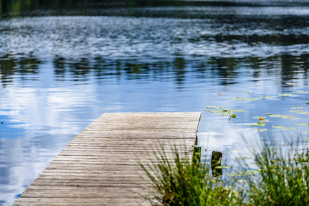 reflection of clouds in the lake with boardwalk and trees in backgroundの写真素材