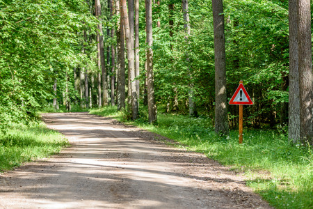 gravel road in sunny summer countryside with perspective and bright red attention signの写真素材