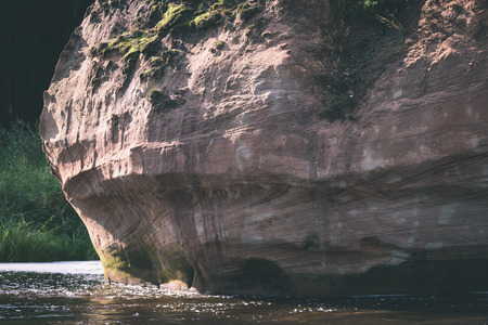 beautyful morning light over forest river of Amata, Cesis, Latvia. sandstone cliffs and green vegetation around water in summer - vintage effectの写真素材