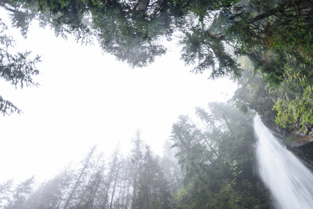 large Waterfall falling from sky in autumn, long exposure, in mountain river with rocks and tourist trail stairsの写真素材